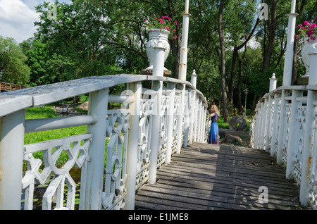 alte Holzbrücke mit weißen wackeln Geländer und Mädchen am Ende der Brücke ruht Stockfoto