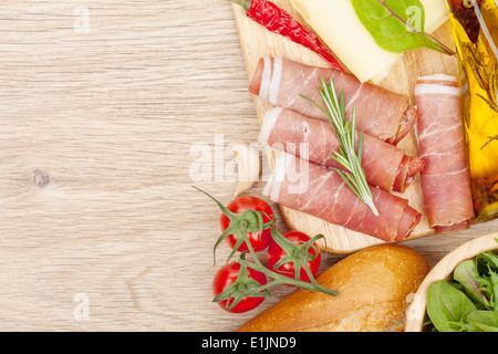 Käse, Schinken, Brot, Gemüse und Gewürze. Über Holztisch Hintergrund mit Textfreiraum Stockfoto