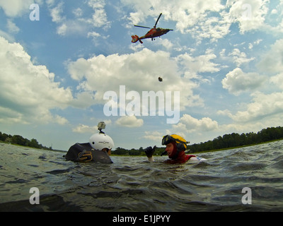 Rettungsschwimmer der U.S. Coast Guard Jason Foyne, Recht, spricht mit Air Force Captain Brian Bradke als ein HH - 65C Dolphin Coast Guard helic Stockfoto