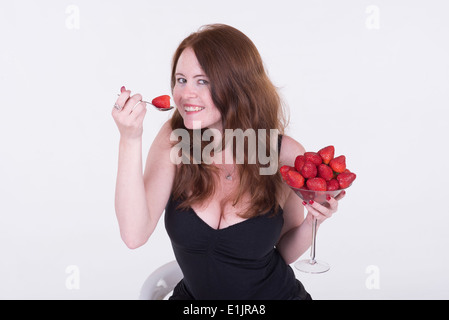 Porträt einer jungen Frau mit roten Haaren, Essen Erdbeeren Stockfoto