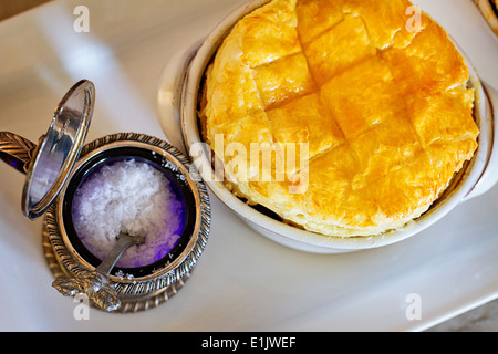 Salz in einem antiken Behälter neben einem hausgemachten Kuchen Hähnchengerichte Stockfoto