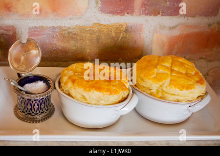 Salz in einem antiken Behälter neben zwei kleinen Hähnchengerichte Torte Stockfoto