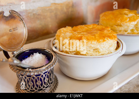 Salz in einem antiken Behälter neben zwei kleinen Hähnchengerichte Torte Stockfoto
