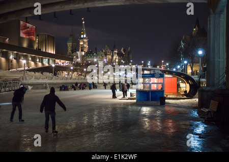 Rideau Eislaufbahn und das Parlament in der Nacht. Skater auf der Rideau Canal Skateway vor der NAC mit der Flut beleuchtete Parlament Stockfoto