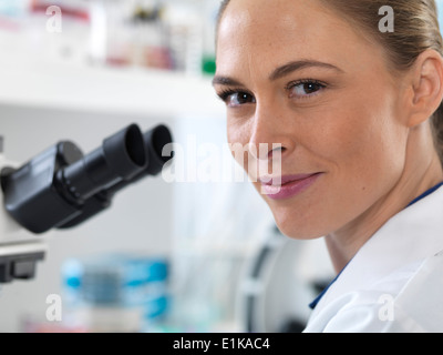 Porträt der Wissenschaftlerin durch ein Mikroskop. Stockfoto