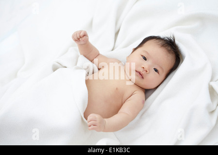 MODEL Release Baby Girl auf weißer Bettwäsche Porträt liegen. Stockfoto