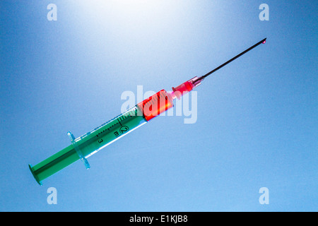 Spritze mit roter Flüssigkeit auf blauem Grund. Stockfoto