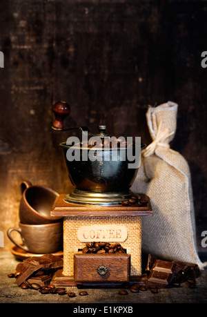 Einem Leben mit Antik Kaffeemühle, Leinensack, Kaffeetassen und Schokolade auf rustikalen Tisch Stockfoto