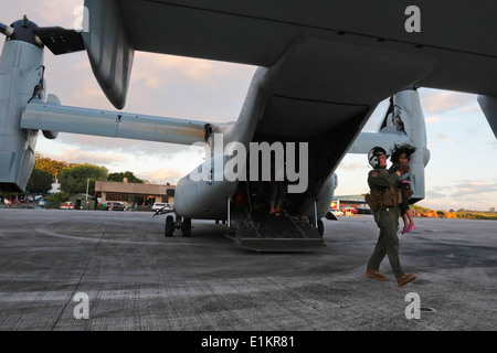 U.S. Marine Corps CPL Zachary Lyon, ein Crewchef mit Marine Medium Tiltrotor Squadron (VMM) 262, trägt ein Kind aus einem Mar Stockfoto