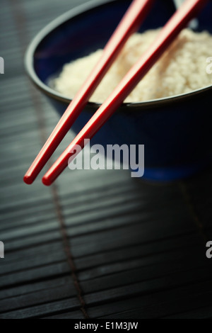 Schüssel mit Reis und Stäbchen über schwarz Stockfoto