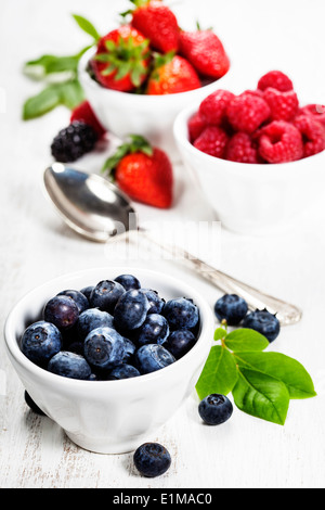 Beeren in Schalen auf hölzernen Hintergrund. Erdbeeren, Himbeeren und Heidelbeeren. Gesundheit, Ernährung, Gartenbau, Ernte-Konzept Stockfoto