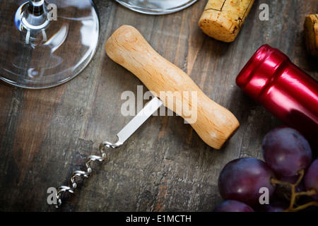 Wein, Trauben, Gläser und Korkenzieher auf hölzernen Hintergrund Stockfoto