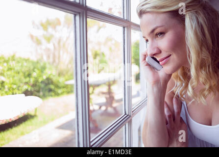 Hübsche Blondine sitzen am Fenster auf einen Anruf Stockfoto
