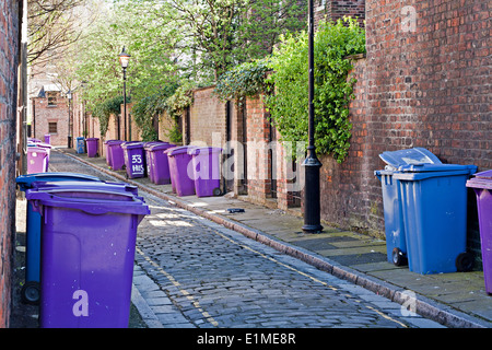 Wheelie-Kästen aufgereiht auf schmalen gepflasterten Straße Stockfoto