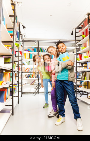 Vier glückliche Kinder in einer Reihe mit Büchern Stockfoto