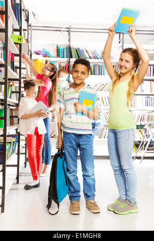 Mädchen versucht, junge mit Buch in der Bibliothek getroffen Stockfoto