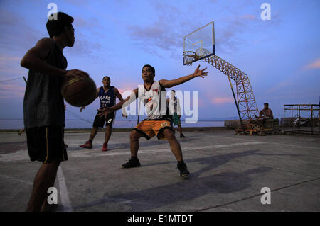 Dumaguete, Negros Oriental, Philippinen. 4. Juni 2014. Anwohner spielen auf in die Dunkelheit 4. Juni 2014, bei einem Basketballplatz am Meer in Dumaguete City auf der Insel Negros in den Philippinen. PHILLIP PRINS © Phillip Prins/Prensa Internacional/ZUMAPRESS.com/Alamy Live-Nachrichten Stockfoto