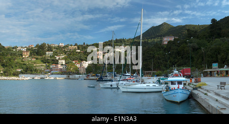 Angelboote/Fischerboote und Yachten vor Anker im Hafen von Poros, Kefalonia, als das letzte Licht des Tages scheint auf die Häuser am Hang. Stockfoto