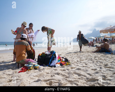 RIO DE JANEIRO, Brasilien - ca. März 2013: Kunden versuchen auf Ware von einem Händler in eine typische Szene am Strand von Ipanema. Stockfoto