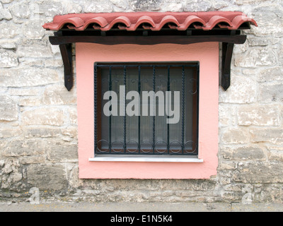 Farbenfrohe Fensterrahmen inmitten einer Steinmauer Stockfoto