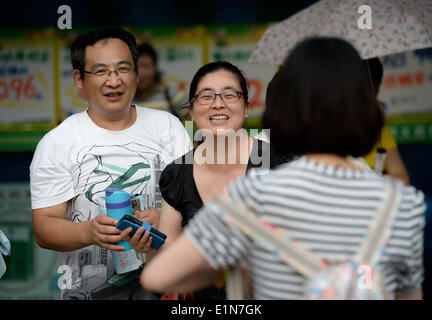 Chengdu, China Reisedaten Provinz. 7. Juni 2014. Zwei Eltern Grüßen ihre Tochter, die gerade den Mathetest von der nationalen Hochschule Eingang Prüfung (NCEE) an der Zhonghe High School in Chengdu, Hauptstadt der Südwesten Chinas Reisedaten Provinz, 7. Juni 2014 beendet hat. Chinas 2014 nationalen College-Aufnahmeprüfung begann am Samstag. Die zweitägige Prüfung beschäftigt nicht nur 9,4 Millionen Teilnehmer, sondern auch viele Eltern. © Li Qiaoqiao/Xinhua/Alamy Live-Nachrichten Stockfoto