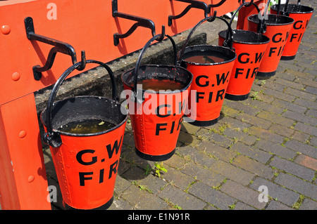 Reihe von roten viktorianischen Feuer Eimer auf dem Bahnsteig, Hampton Loade, Shropshire, England, Vereinigtes Königreich, West-Europa. Stockfoto