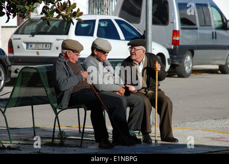 Drei ältere spanische Männer sitzen auf einer Bank im Chat, weiß getünchten Dorf Canillas de Aceituno, Andalusien, Spanien. Stockfoto