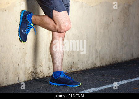 Männliche Läufer lehnt sich entspannt gegen die Wand. Stockfoto