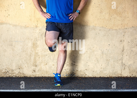 Männliche Läufer lehnt sich entspannt gegen die Wand. Stockfoto