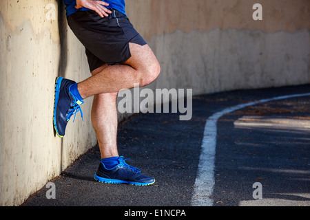 Männliche Läufer lehnt sich entspannt gegen die Wand. Stockfoto