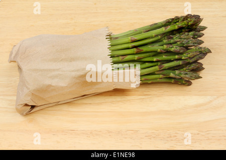 Spargel in braunem Papier auf einem Holzbrett gewickelt Stockfoto