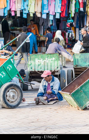 Zwei Männer sitzen hinter Anhänger ein Brettspiel wie Zugluft oder Kontrolleure in Djemaa el-Fna Markt in Marrakesch Stockfoto