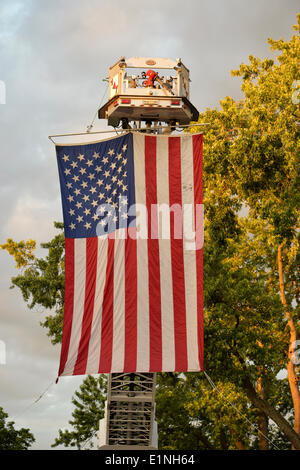 Garden City, New York, USA - 6. Juni 2014 - A große amerikanische Flagge wurde von einer Hubarbeitsbühne hoch über der Kreuzung von Franklin Avenue und 7th Street, während das 17. jährliche Gartenstadt Belmont Stakes-Festival feiert den 146. Betrieb der Belmont Stakes am nahe gelegenen Elmont am nächsten Tag ausgesetzt. Gab es street Festival Familienspaß mit live-Bands, Essen, Ponyreiten und vieles mehr, und ein der Hauptsponsoren dieser Veranstaltung Long Island Nacht war New York Racing Association Inc. Stockfoto