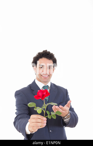 Junge hübscher Geschäftsmann hält rot Stand auf und bietet eine Rose an die Kamera Stockfoto