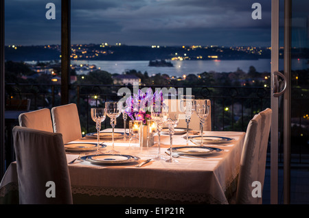 Ein Tisch ausgebreitet auf elegante Weise mit einem schönen Blick auf Sydney Harbour in der Abenddämmerung Stockfoto