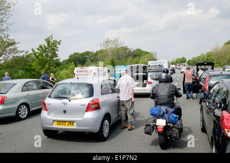 Motorräder, Weben durch stillstehende Fahrzeuge im Stau mit Menschen, die auf M6 Fahrbahn stehen. Lancashire, England, Vereinigtes Königreich Stockfoto