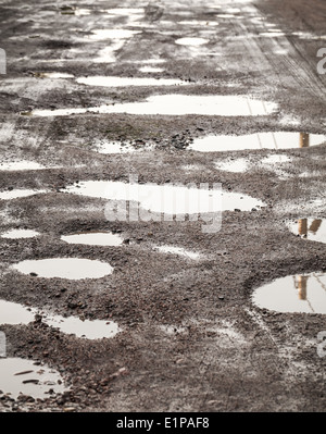 Schmutzige beschädigte Landstraße mit Muds und Löcher Stockfoto