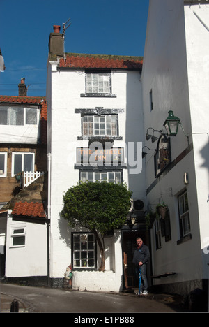 Ein Mann steht vor Laurel Inn in Robin Hoods Bay, Yorkshire. Stockfoto