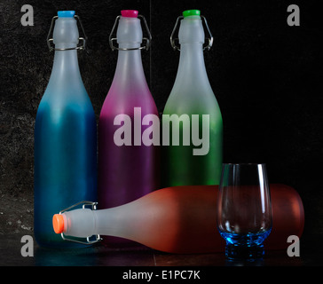 Dramatische rosa, grün, blau und orange Vintage retro-Stil Wasserflaschen mit blauen Tumbler Glas Stilleben Stockfoto
