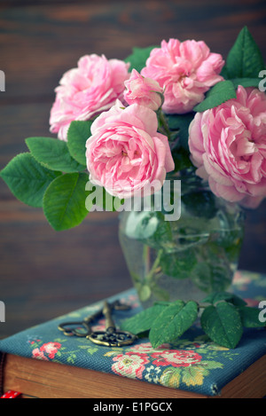 Bouquet von Tee-Rosen in Glasvase auf hölzernen Hintergrund Stockfoto