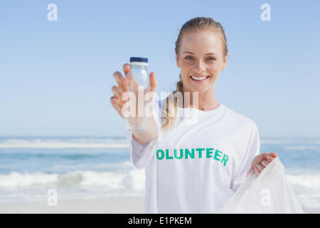 Blonde lächelnde Freiwilligen Abholung Müll am Strand Stockfoto