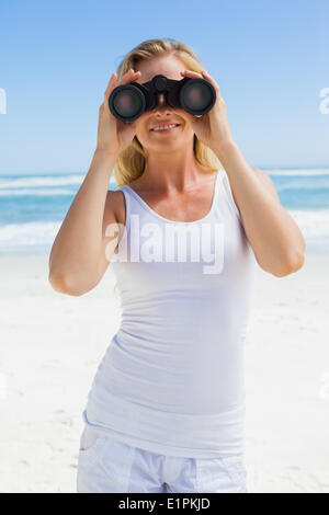 Blondine mit Fernglas am Strand suchen Stockfoto