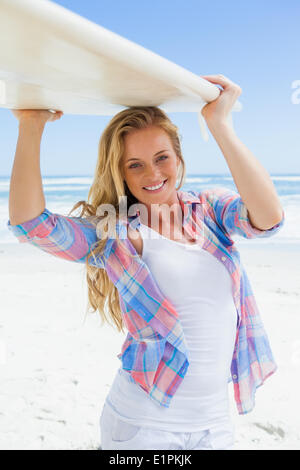 Blonde Surfer ihr Board lächelnd in die Kamera halten Stockfoto