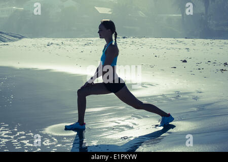 Fit Woman machen Ausfallschritte am Strand Stockfoto