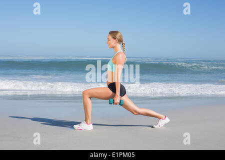 Fit Woman tun gewichteten Ausfallschritte am Strand Stockfoto