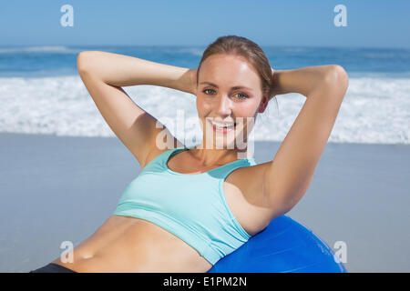 Fit Frau liegt auf Gymnastikball am Strand tun Sit Ups Stockfoto