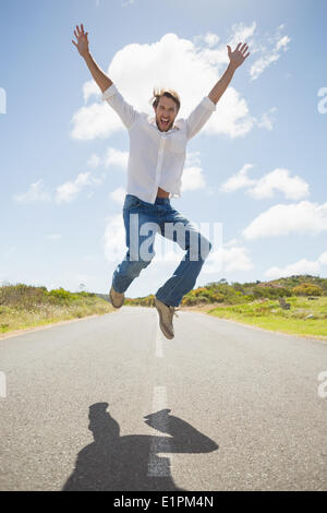 Hübscher legerer Mann springt auf einer Straße in die Kamera Lächeln Stockfoto