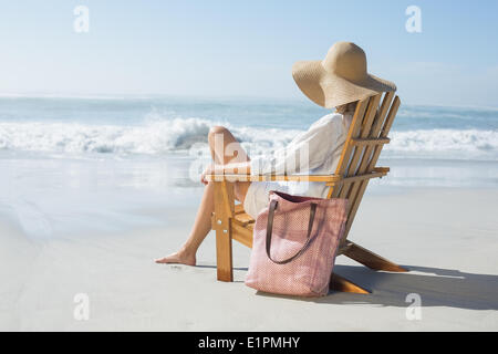 Frau sitzt auf hölzernen Liegestuhl am Meer Stockfoto