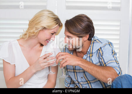 Süße junge Paar sitzt am Boden zusammen mit Weißwein Stockfoto