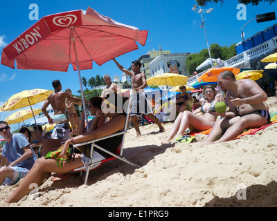SALVADOR, Brasilien - 13. Oktober 2013: Einheimische mischen mit Touristen Entspannung an einem hellen Sommernachmittag am Strand von Porto da Barra. Stockfoto